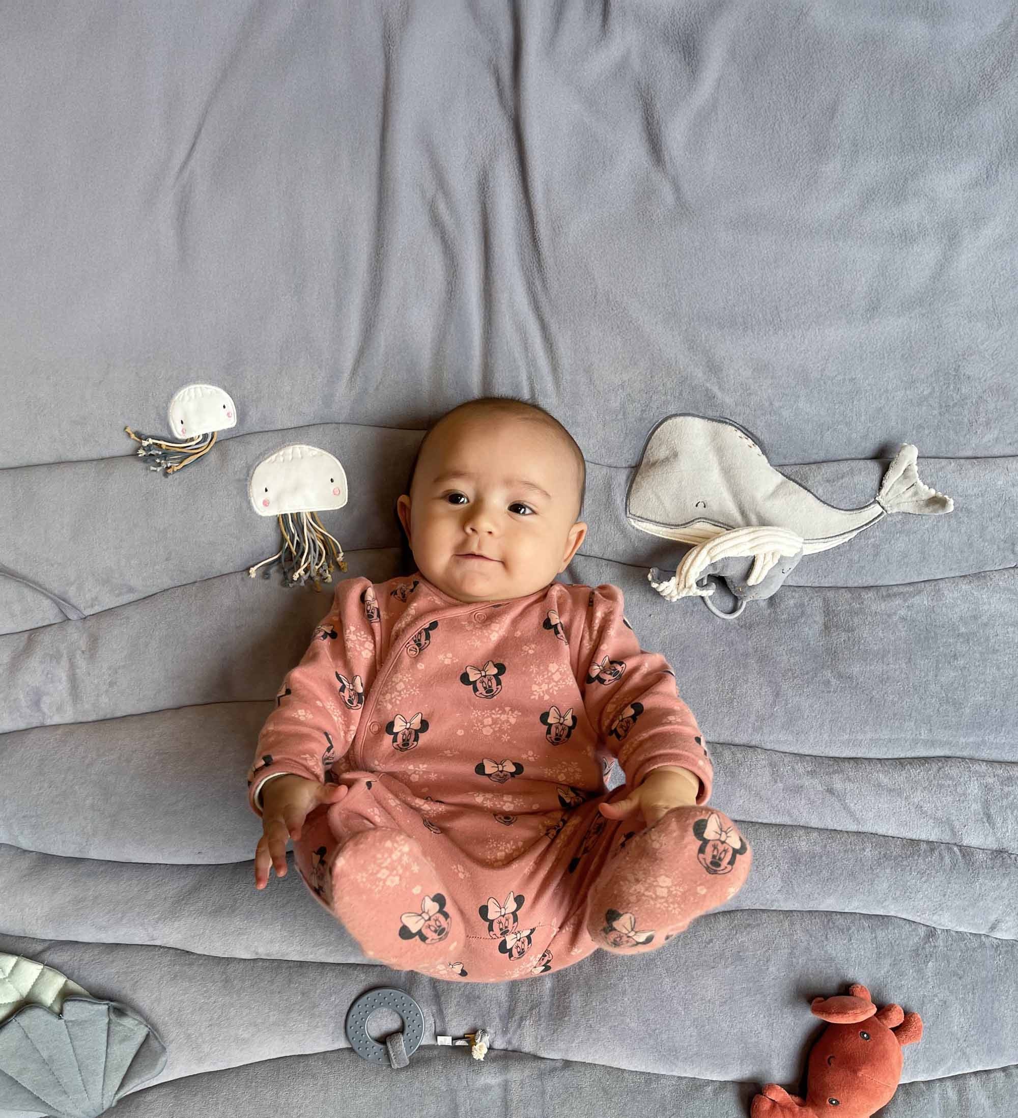 Baby ligt op speelkleed. 