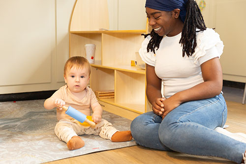 Pedagogisch professional speelt met een dreumes op het kinderdagverblijf. 