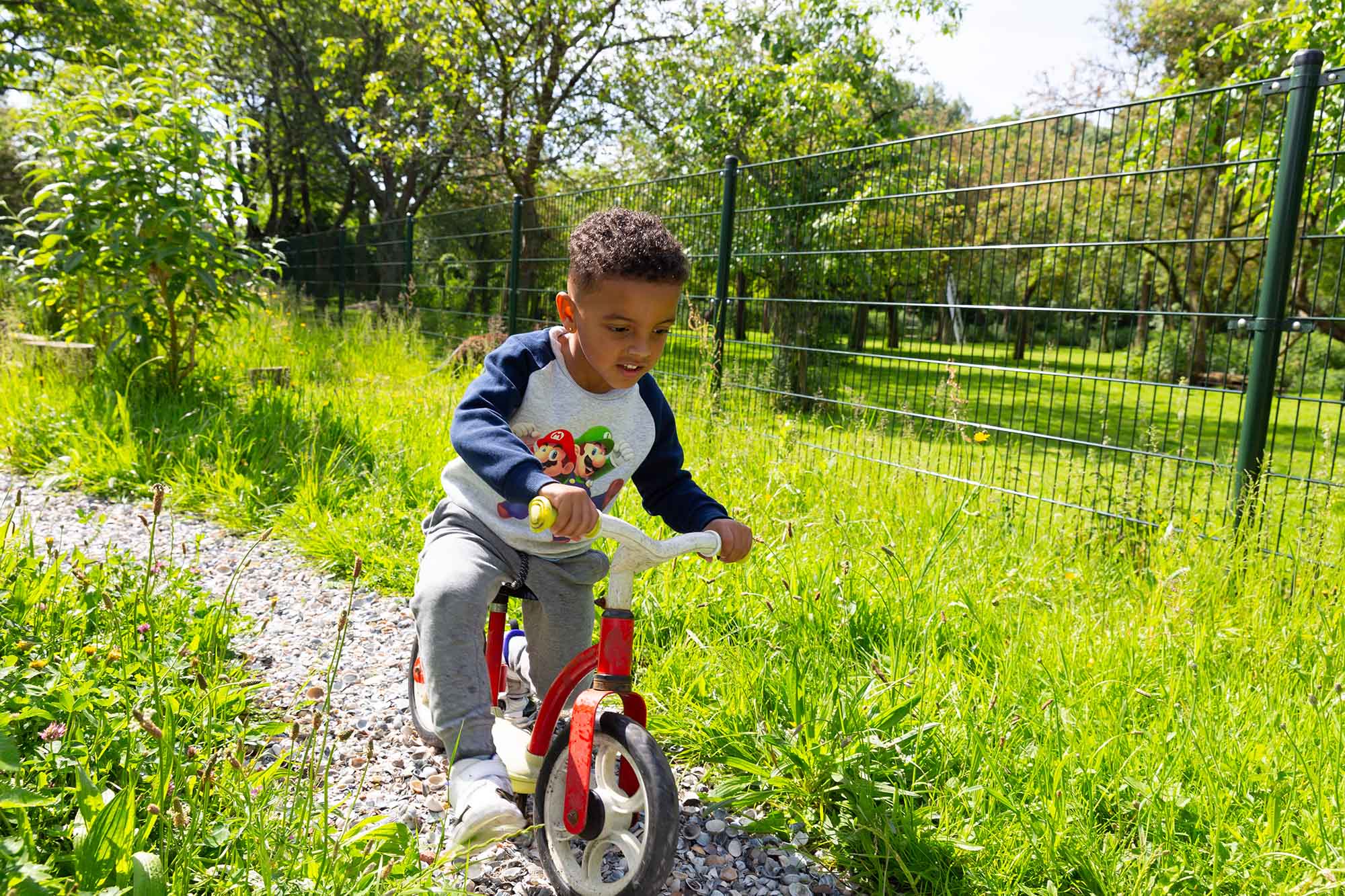 Peuter fietst in het gras bij de peuteropvang. 