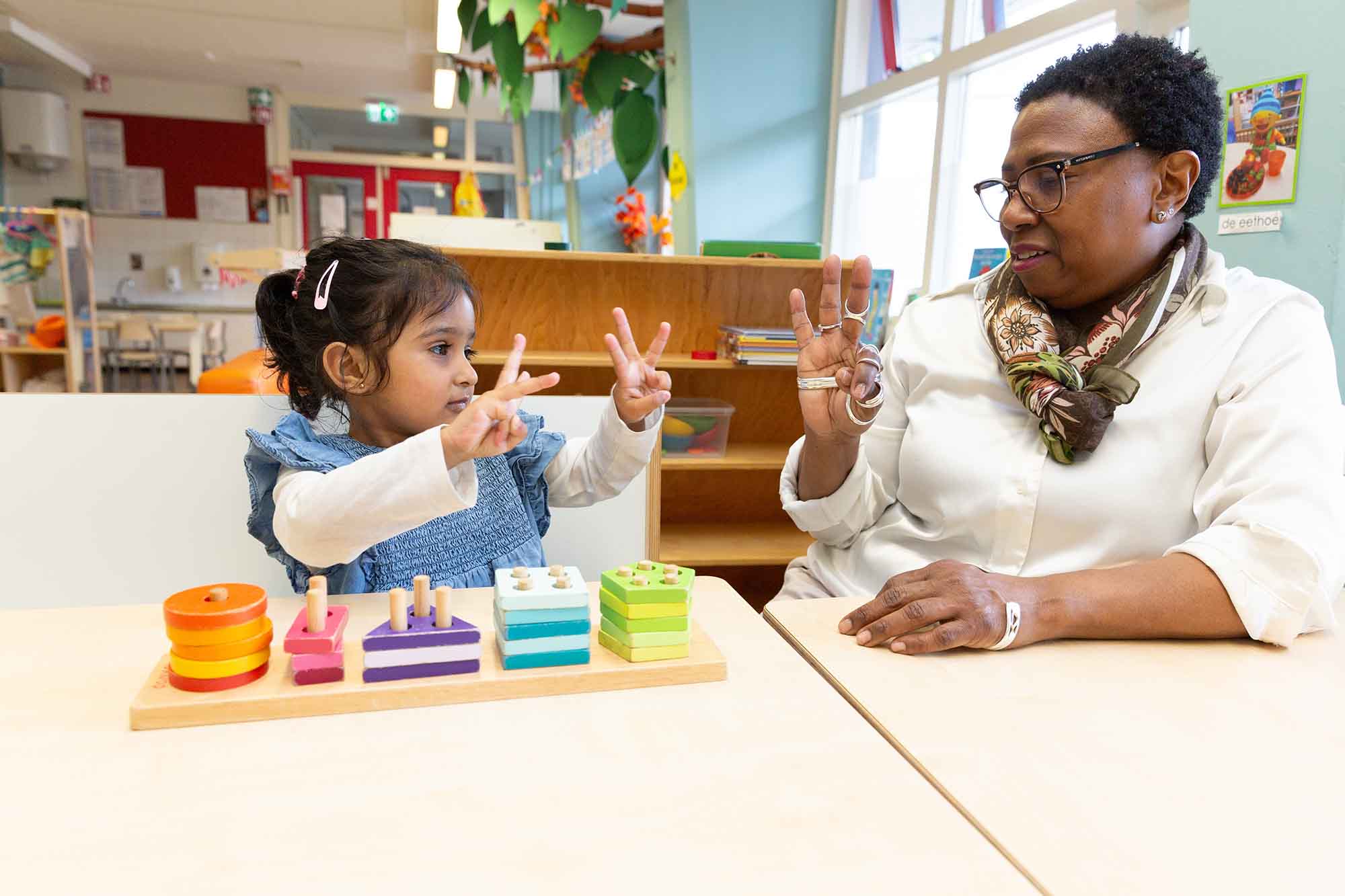 Pedagogisch professional leert een peuter tellen. 