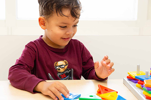 Peuter speelt met educatief spel met vormen op kinderdagverblijf.