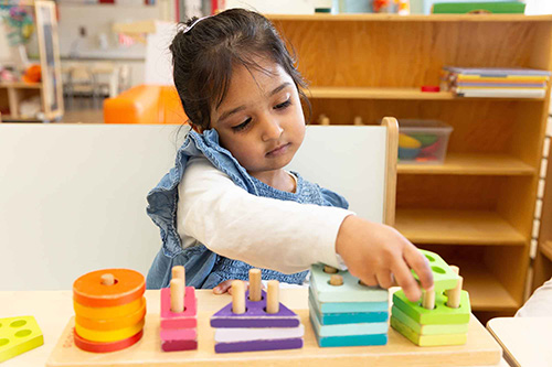 Peuter speelt met educatief vormenspel bij de peuteropvang.