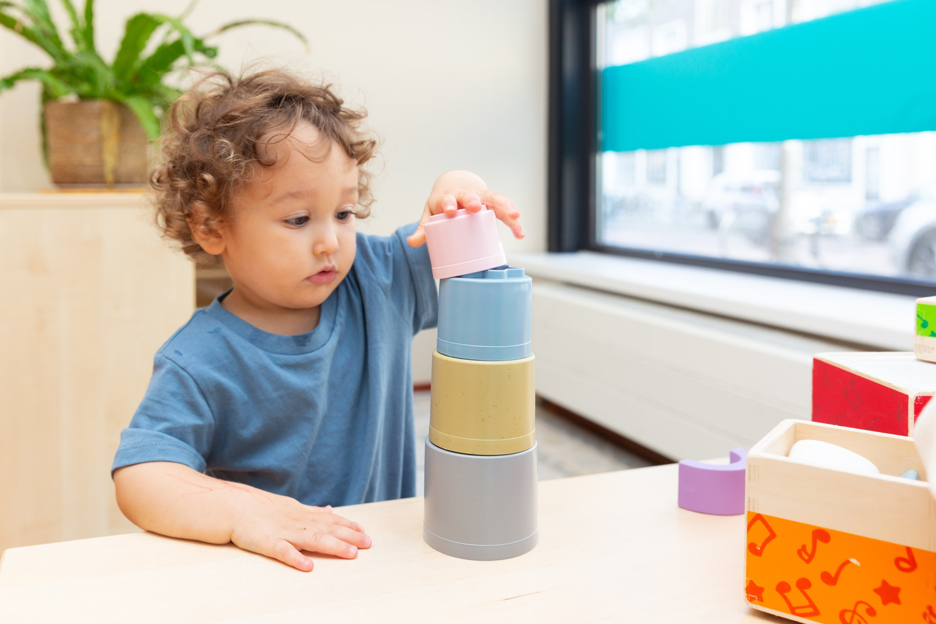 Kind stapelt blokjes op tafel van kinderdagverblijf.