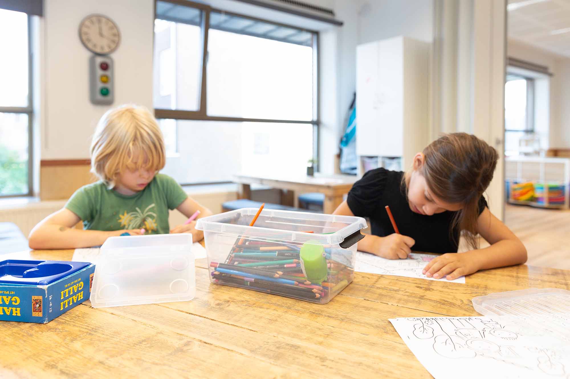 Kinderen maken kleurplaat aan tafel van kinderopvang locatie.