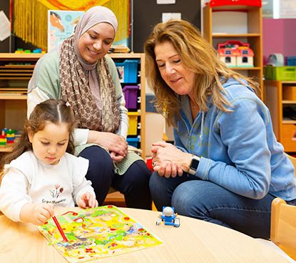 Pedagogisch professionals kijken hoe een peuter een spel doet. 