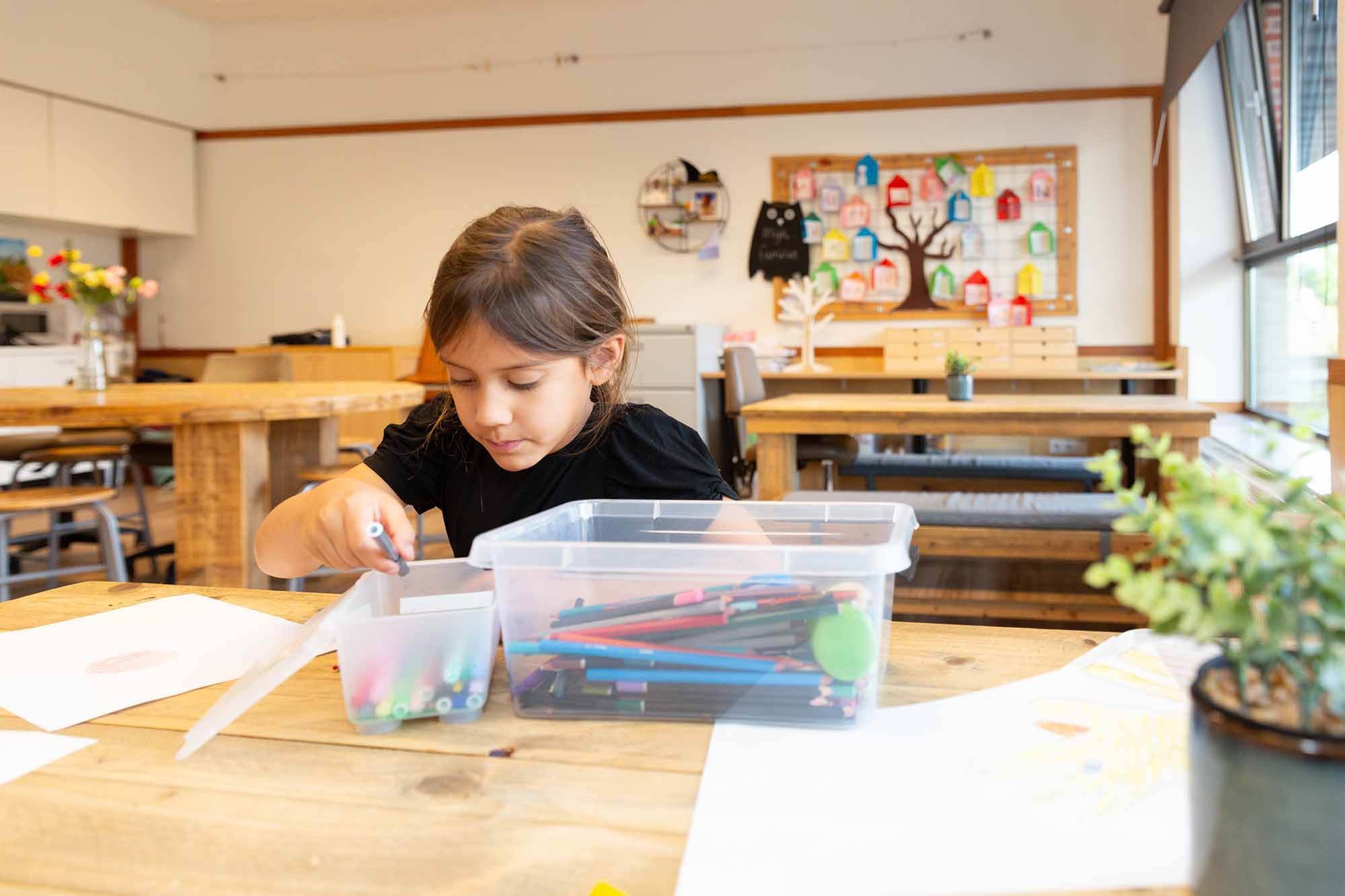 Meisje tekent aan tafel bij kinderopvang locatie.