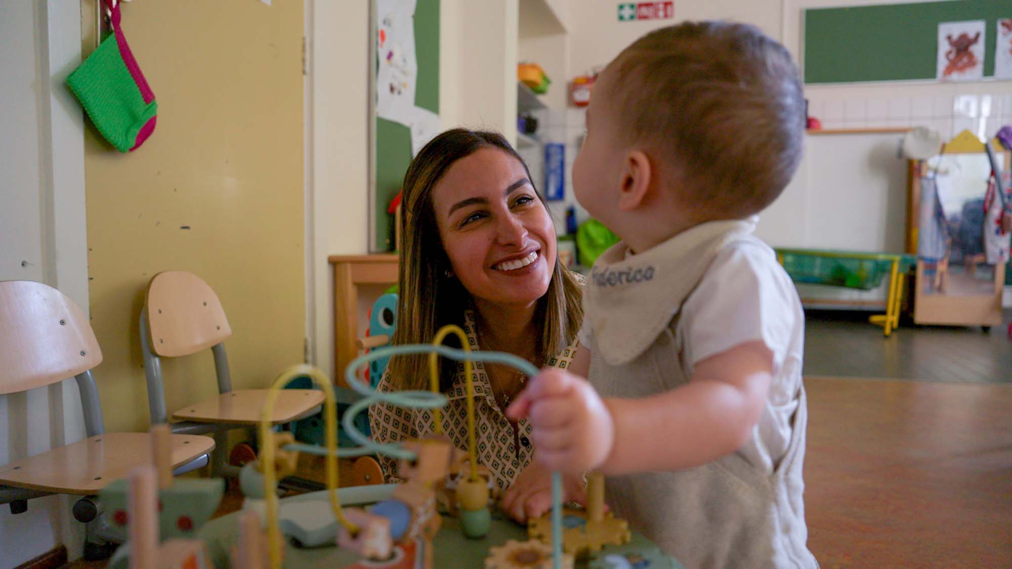 Moeder en dreumes spelen met een kralenspiraal bij samenspeelgroep.