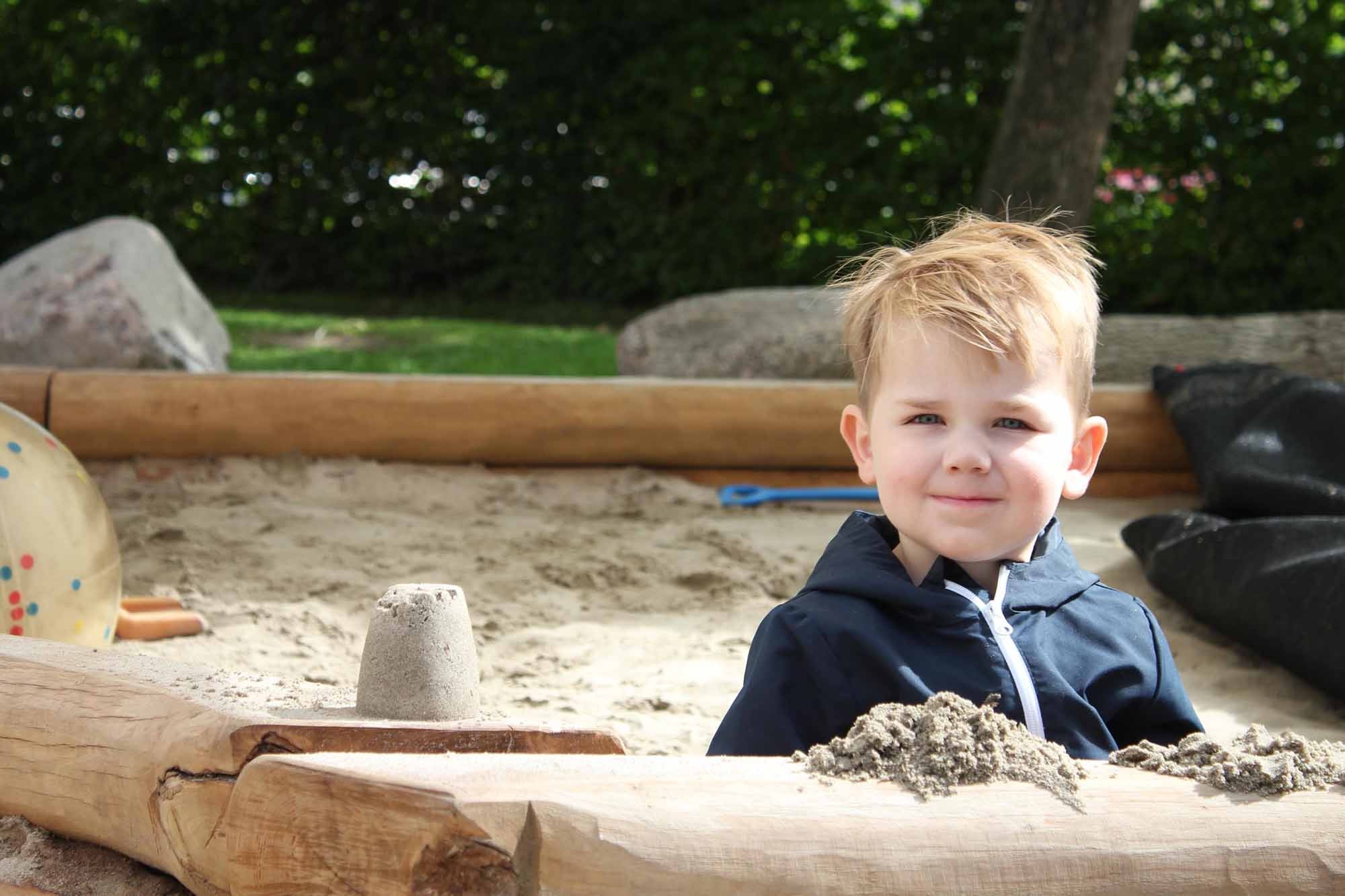 Peuter speelt in de zandbak bij de peuteropvang.