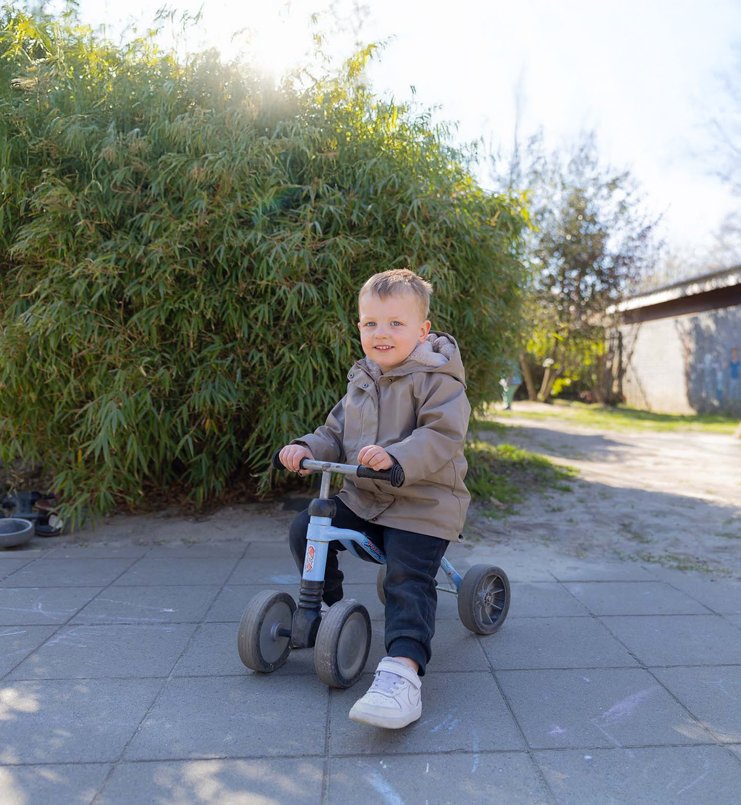 Peuter op een driewieler bij de peuteropvang. 