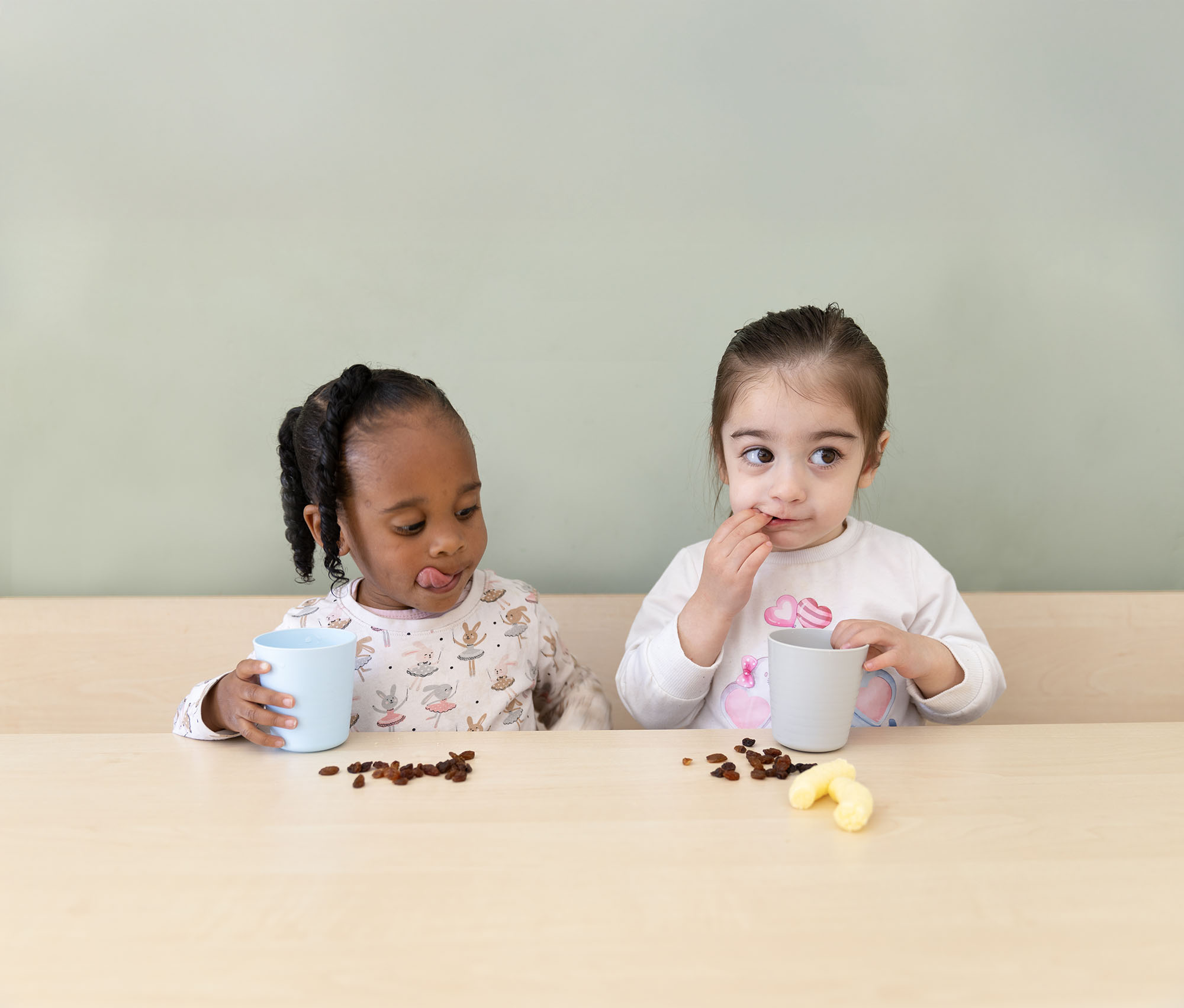 Twee peuters eten rozijntjes op de peuteropvang. 