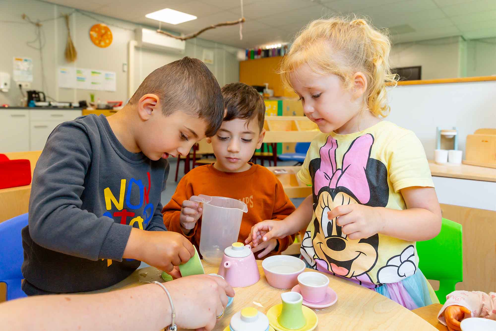 Peuters spelen aan tafel met een theeservies. 
