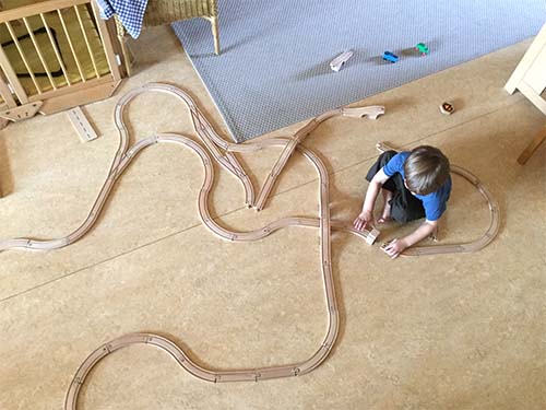 Kind bouwt treinbaan op de grond van een kinderopvang locatie.