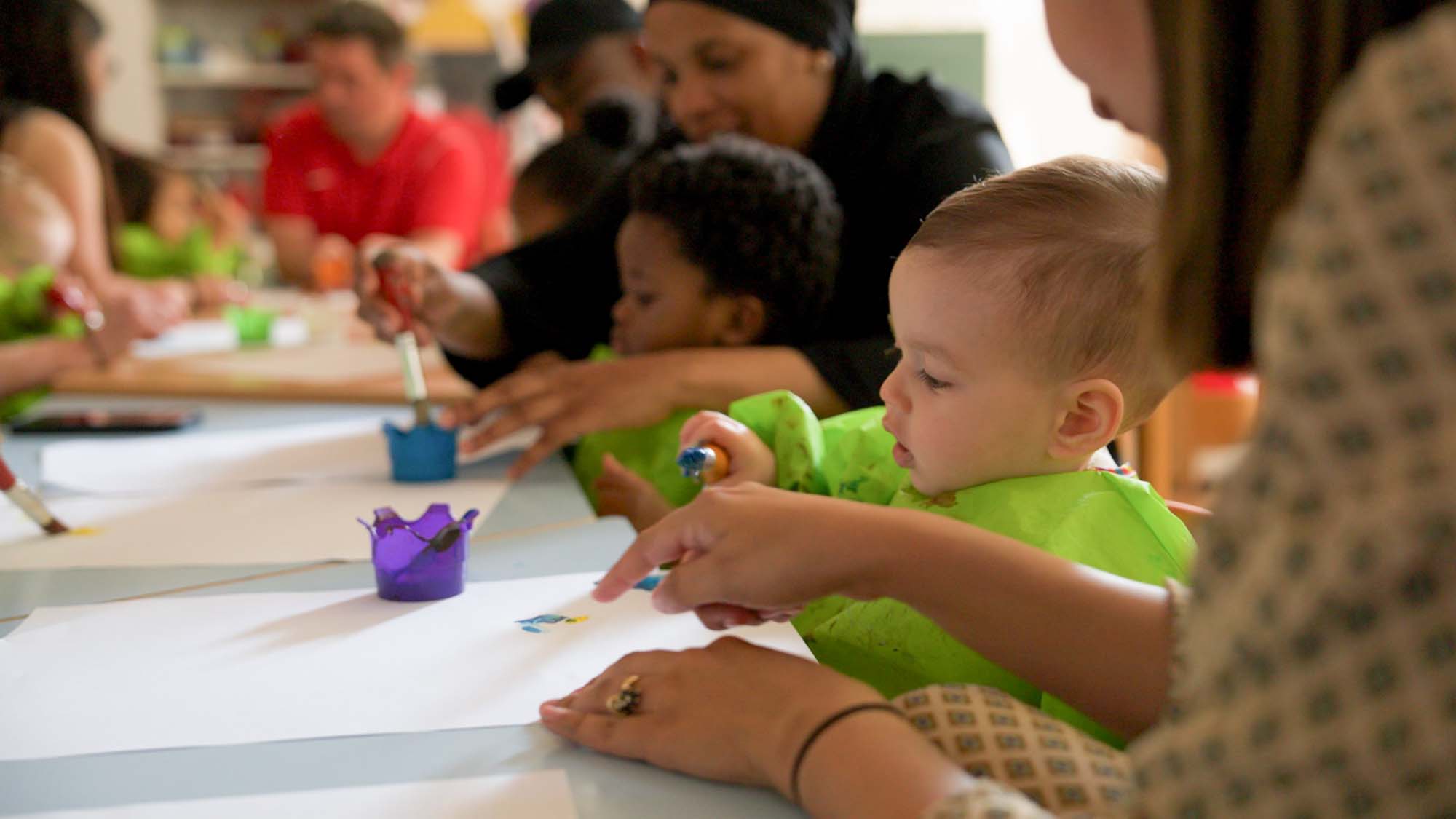 Ouders en kinderen verven samen bij de samenspeelgroep.