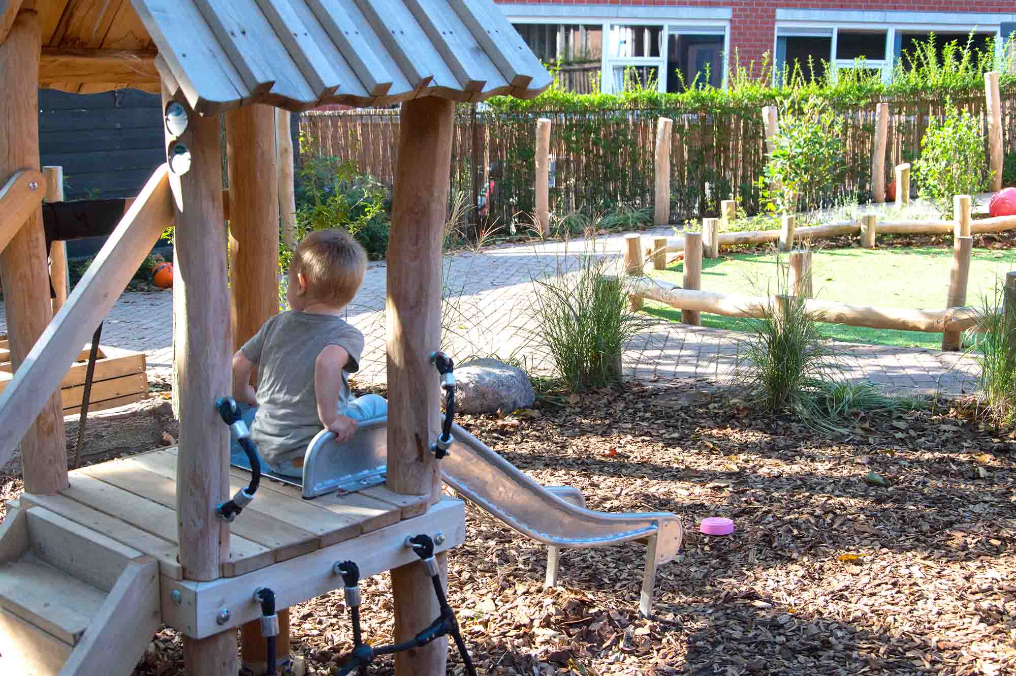 Kind op een glijbaan in de tuin van het kinderdagverblijf. 
